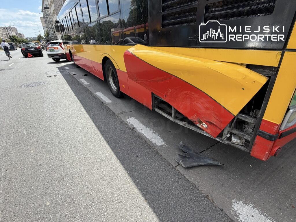 Autobus miejski z uszkodzoną tylną częścią stoi na jezdni, obok zaparkowane samochody.