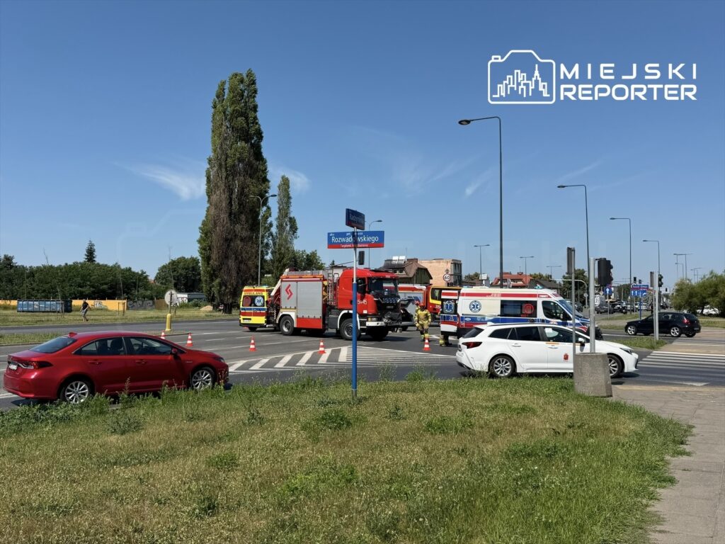 Na rondzie interweniują strażacy i karetki, a ruch jest kierowany przez policję. W tle widoczne budynki.