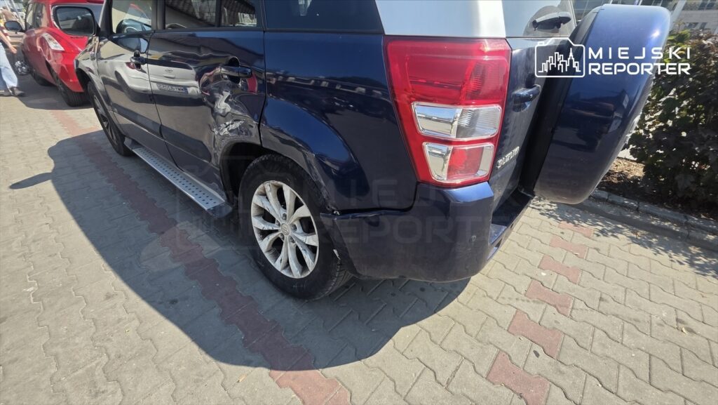 Ciemnoniebieski SUV zaparkowany na chodniku, z widocznymi zarysowaniami na tylnej karoserii.
