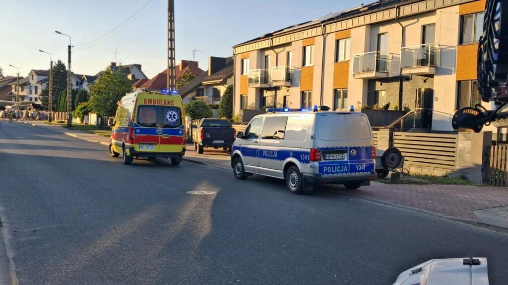 Karetka pogotowia oraz radiowóz policji zatrzymane na ulicy w osiedlu domów jednorodzinnych.