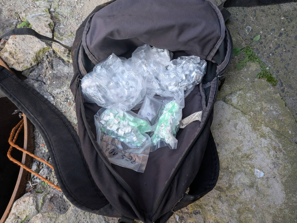Czarna torba leżąca na ziemi, wypełniona foliowymi pakunkami z substancjami chemicznymi.