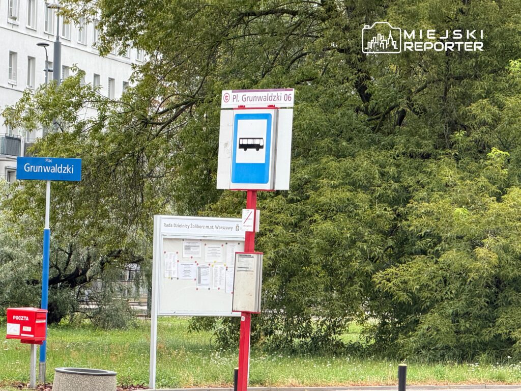 Przystanek autobusowy "Plac Grunwaldzki 06" z oznaczeniem linii, obok tablica ogłoszeń i skrzynka pocztowa.