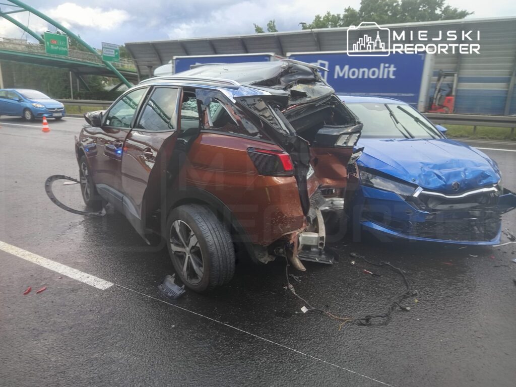 Dwa uszkodzone samochody osobowe na drodze, jeden brązowy z zniszczonym tyłem, drugi niebieski z wgnieceniem z przodu.
