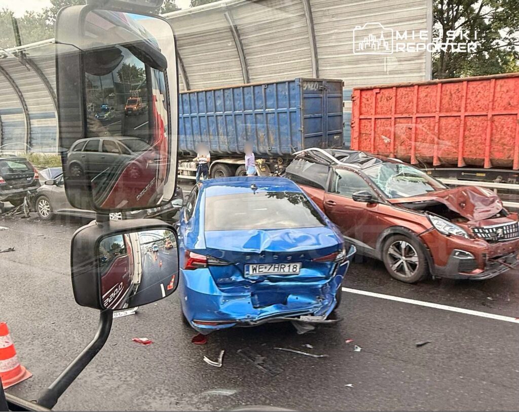 Wielokrotny wypadek drogowy z uszkodzonymi samochodami osobowymi na jezdni, w tle ciężarówki.