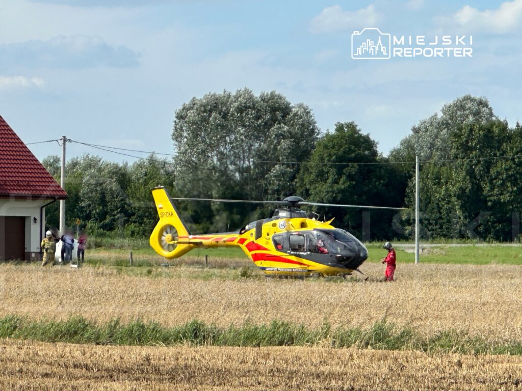 Śmigłowiec ratunkowy ląduje na polu, a zespół medyczny udziela pomocy poszkodowanym w pobliżu domu.