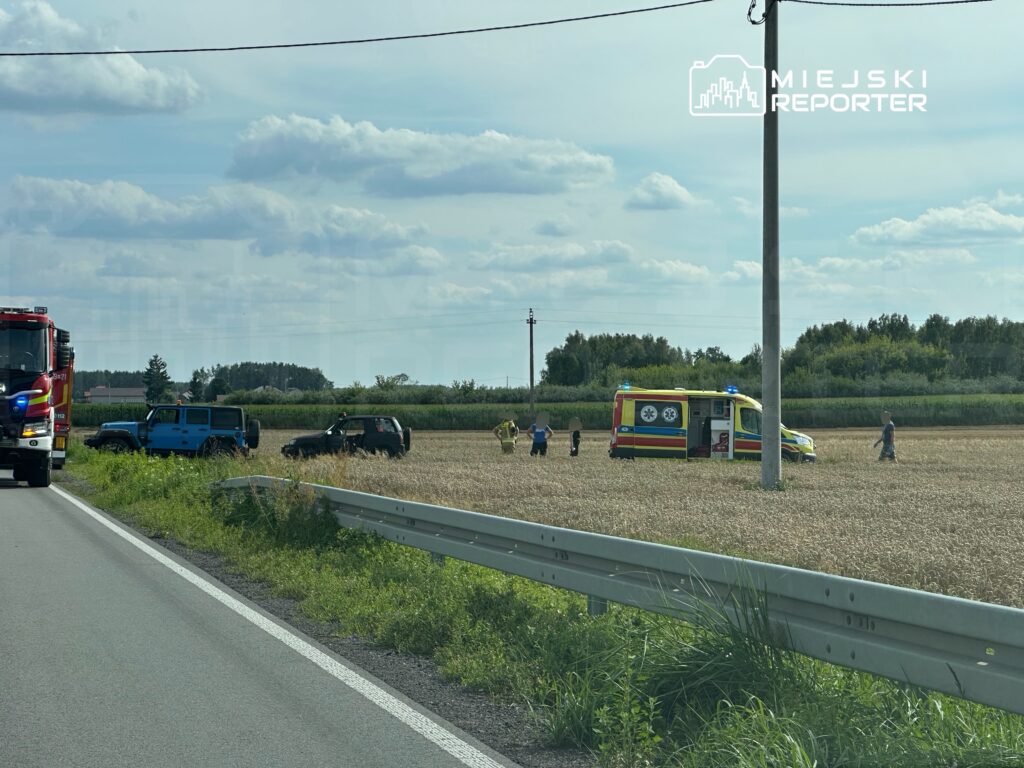 Na drodze obok pola stoją dwa samochody terenowe, a obok nich zespół ratunkowy sprawdzający sytuację.