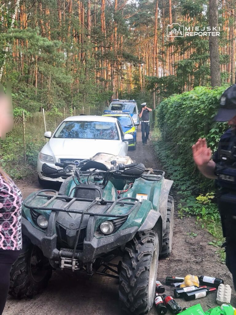Kobieta w bluzce w geometryczny wzór stoi obok quadów, a policjanci interweniują w leśnej okolicy.