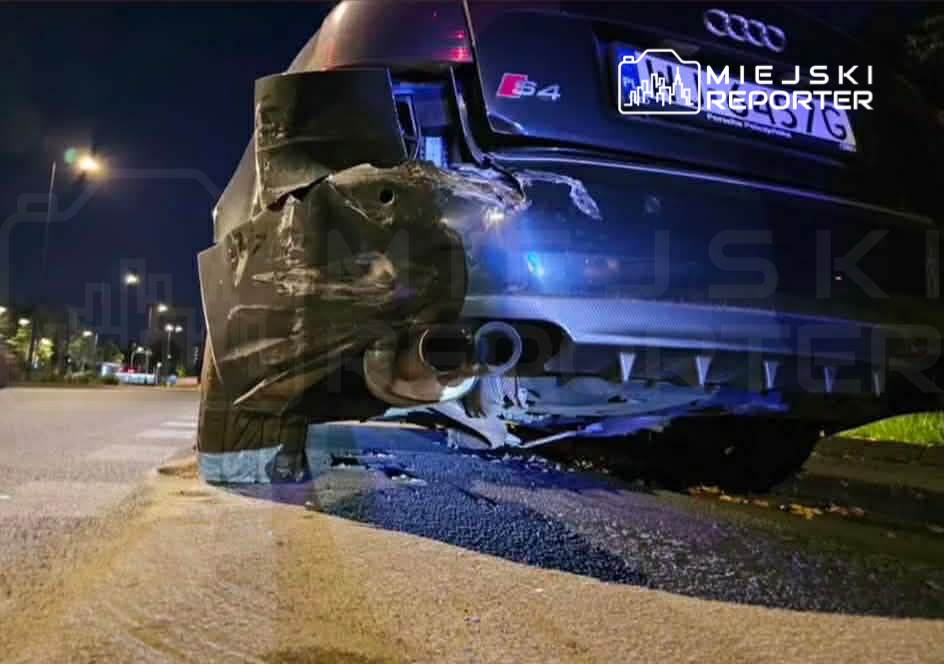 Uszkodzony tył czarnego Audi S4 na poboczu drogi, z widocznymi śladami kolizji i uszkodzeniami zderzaka.