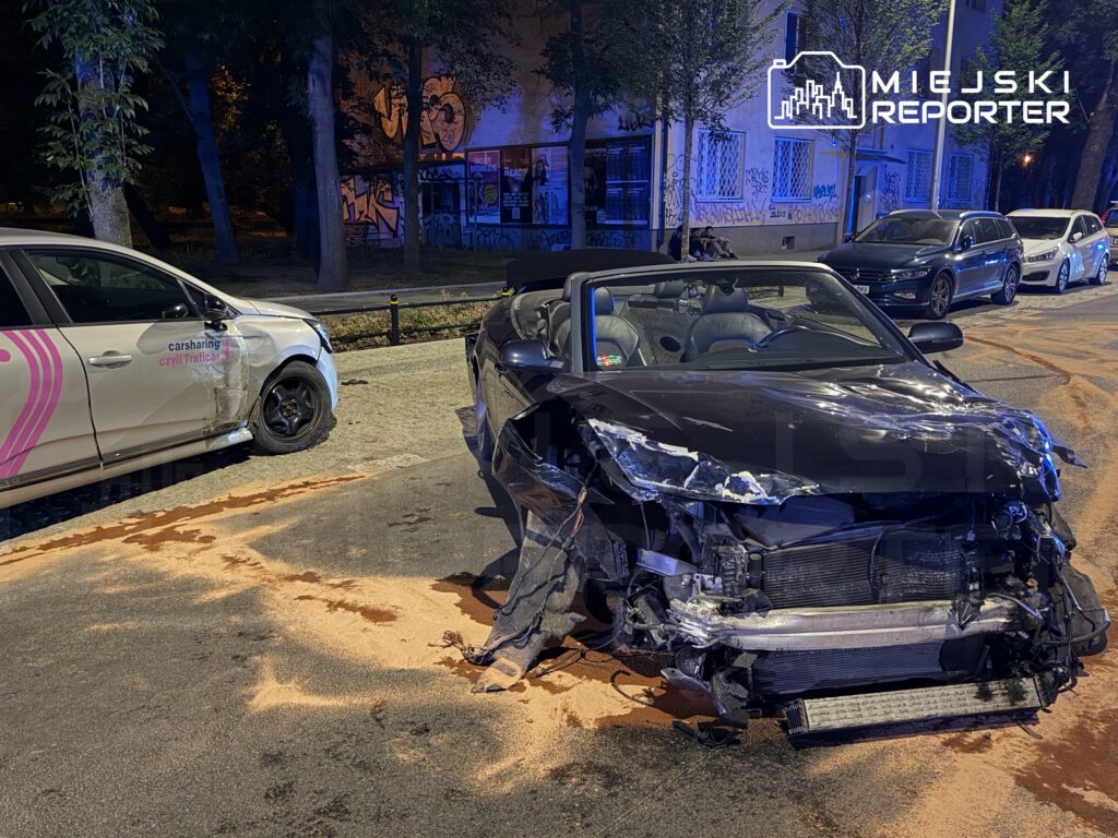 Dwa uszkodzone samochody zaparkowane na ulicy, z widocznymi śladami kolizji i plamami oleju na jezdni.
