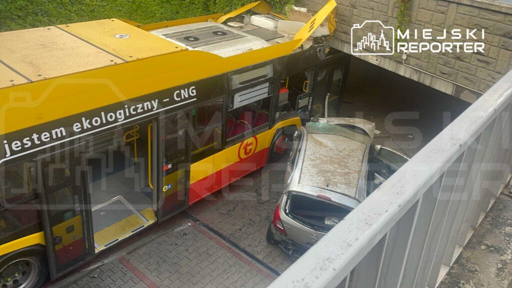 Autobus z uszkodzoną dachową częścią stoi obok uszkodzonego samochodu w podziemnym garażu.