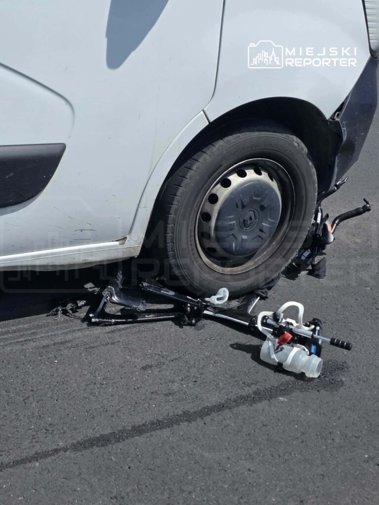 Uszkodzony samochód dostawczy z odłączonym kołem na drodze, obok widoczny mechanizm hamulcowy.