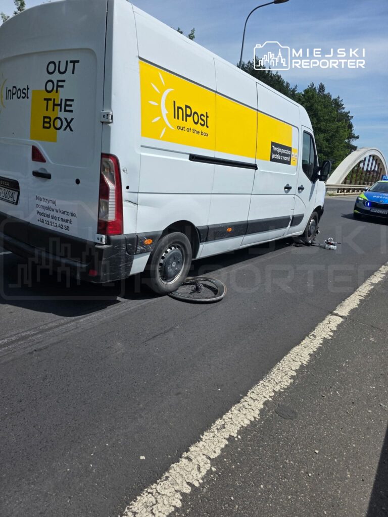 Furgonetka kurierska InPost z uszkodzoną oponą zatrzymana na drodze, obok leży odłączone koło.