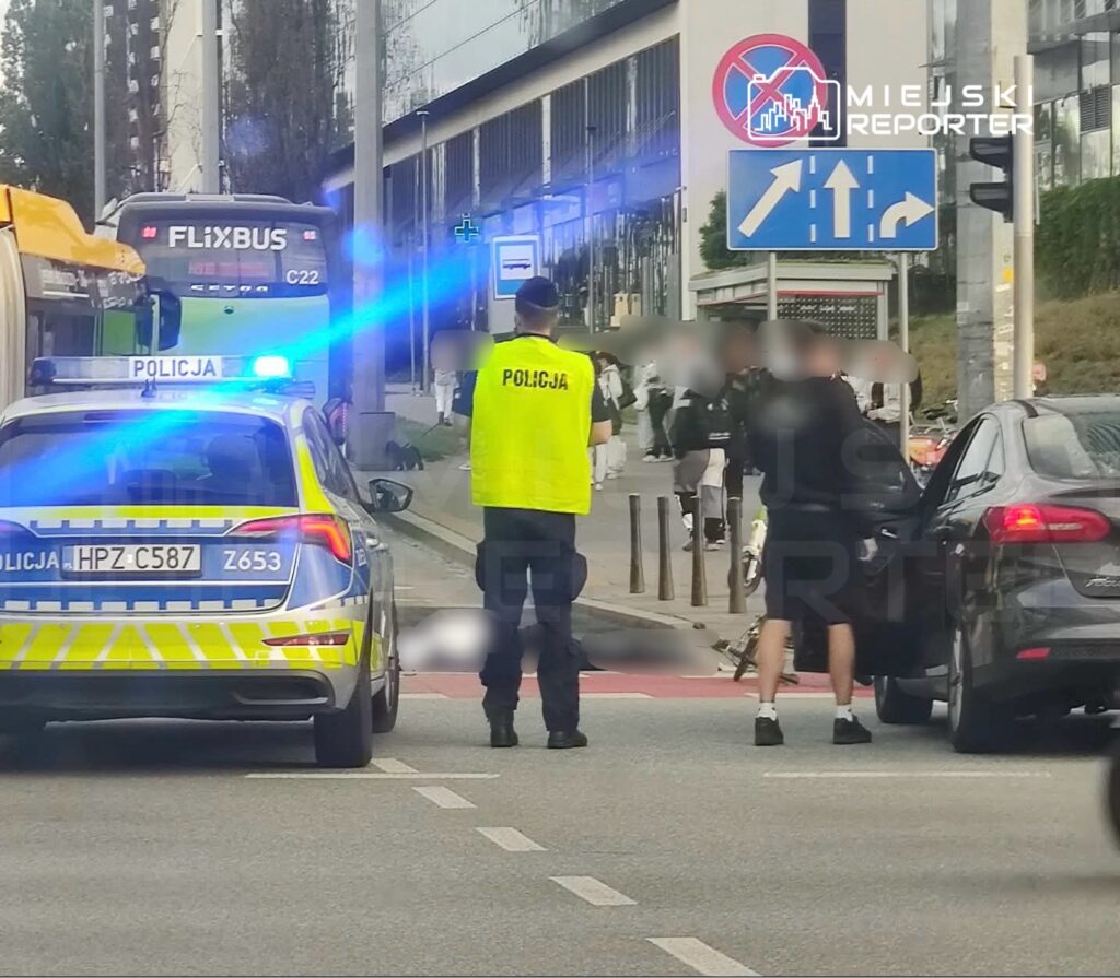 Policjant w odblaskowej kamizelce kontroluje sytuację na ulicy obok zaparkowanego samochodu oraz autobusu FlixBus.