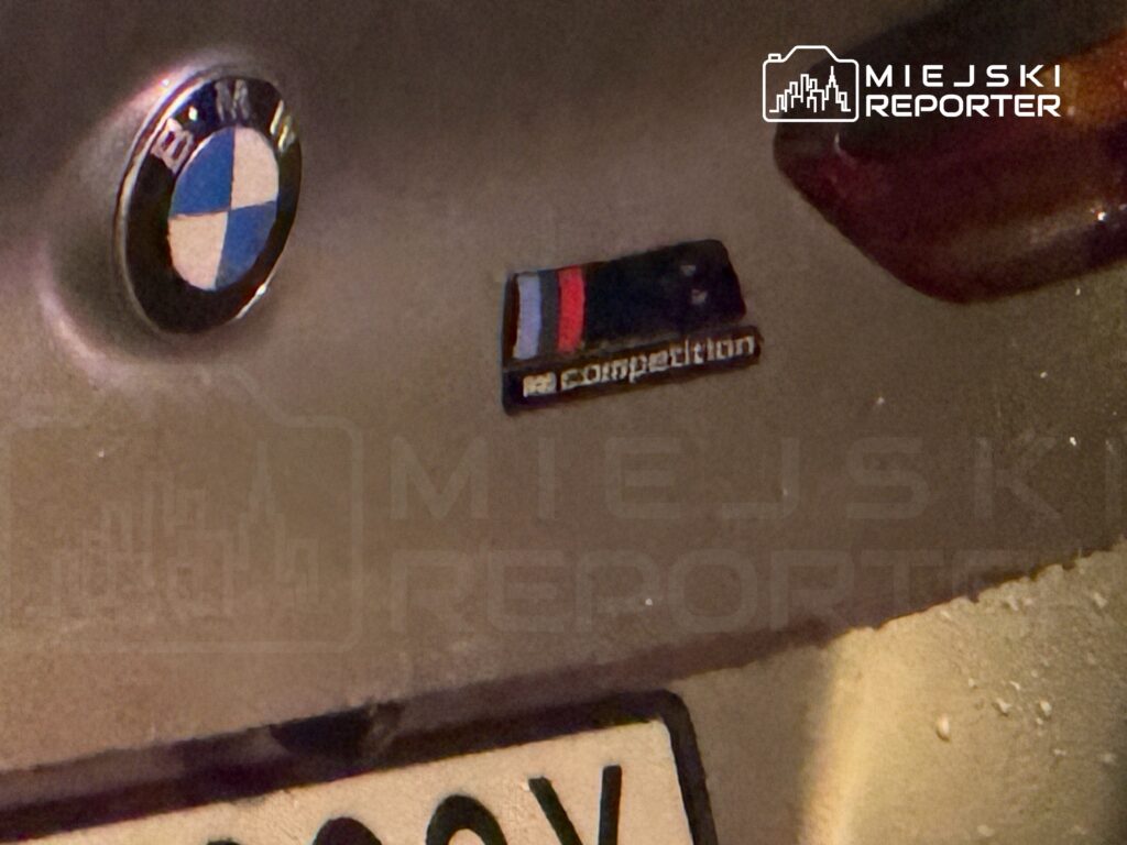 Logo BMW oraz emblemat "M competition" umieszczone na tylnej części samochodu.