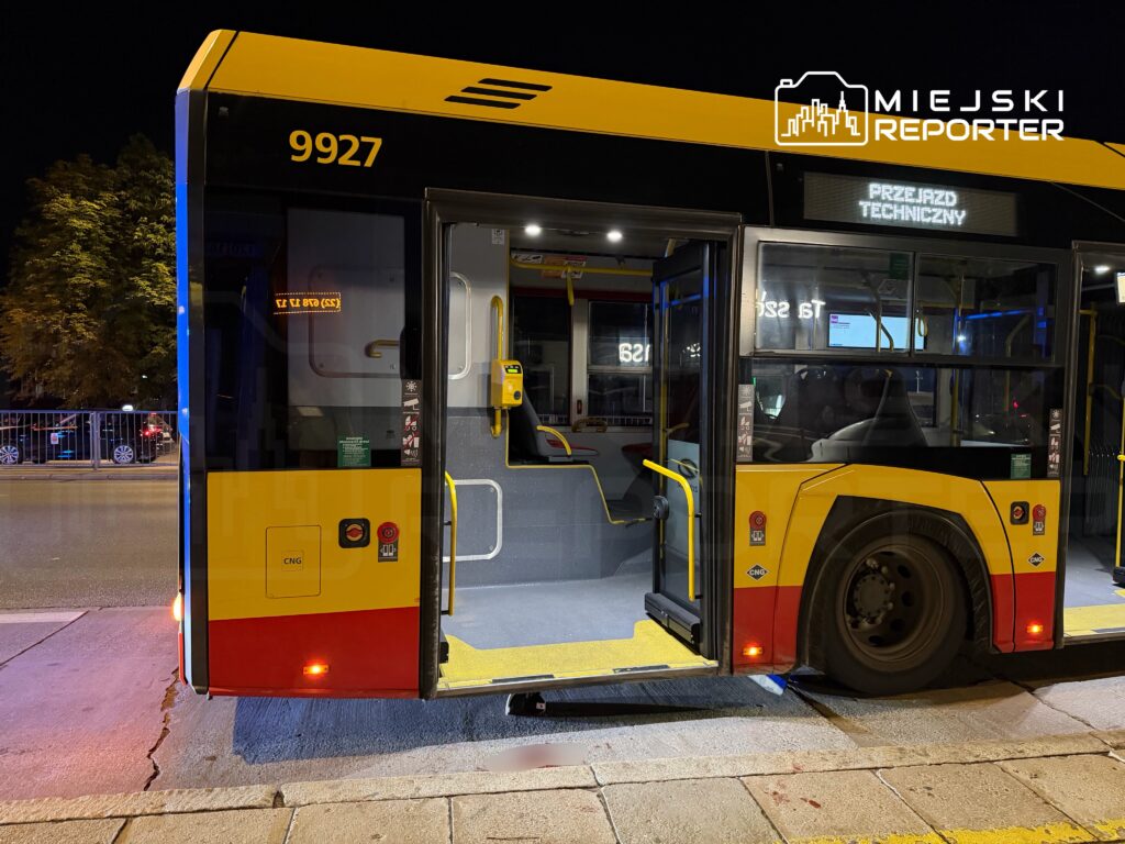Autobus komunikacji miejskiej z numerem 9927 zatrzymany na przystanku, z otwartymi drzwiami, w nocy.