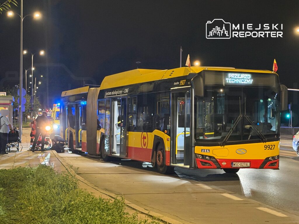 Autobus miejski z numerem 9927 zatrzymany na ulicy, wokół niego pracują ratownicy medyczni i policja.