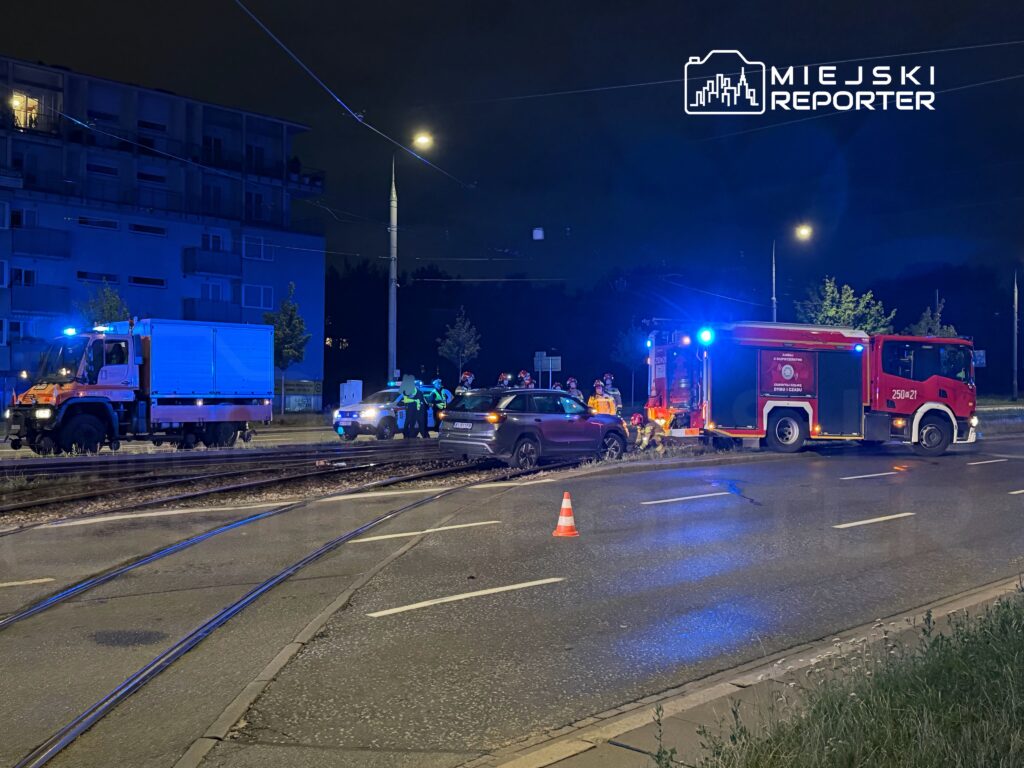W nocy zespół ratunkowy oraz policja interweniują przy wypadku drogowym, obok uszkodzonego pojazdu.