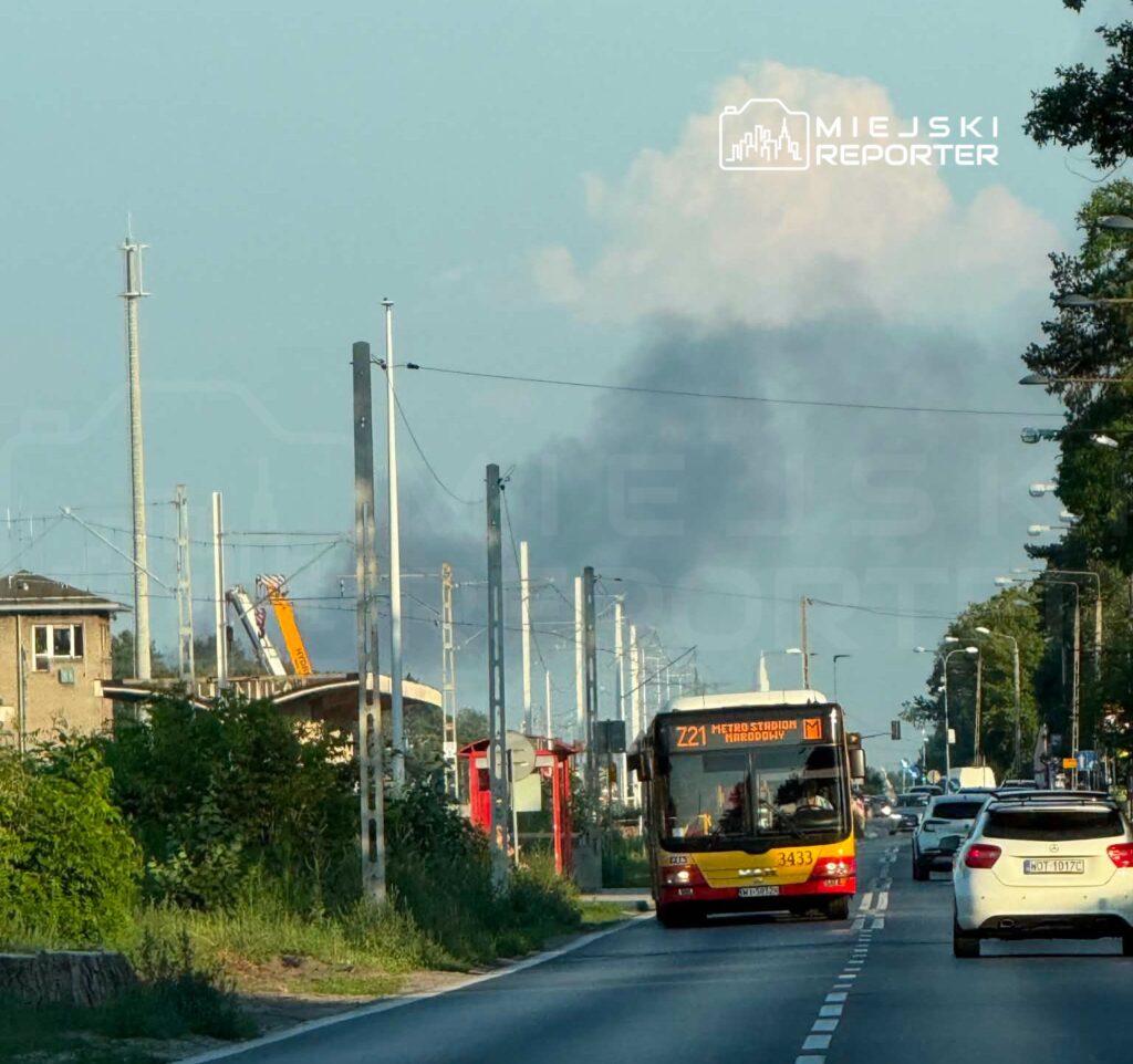 Autobus komunikacji miejskiej z numerem linii 721 jedzie w kierunku stacji metra, w tle widoczny dym.