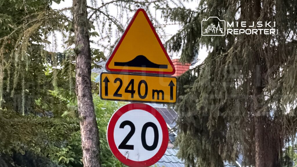 Znak drogowy informujący o spowolnieniu do 20 km/h z ostrzeżeniem o wzniesieniu 240 m przed kierowcą.