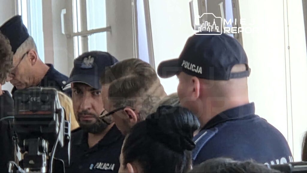 Grupa policjantów w mundurach, z widocznymi emblematami, rozmawia w jasnym pomieszczeniu.