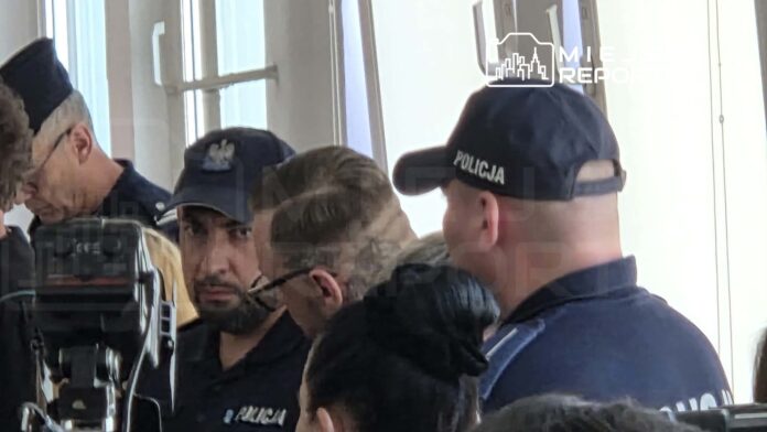 Grupa policjantów w mundurach, z widocznymi emblematami, rozmawia w jasnym pomieszczeniu.