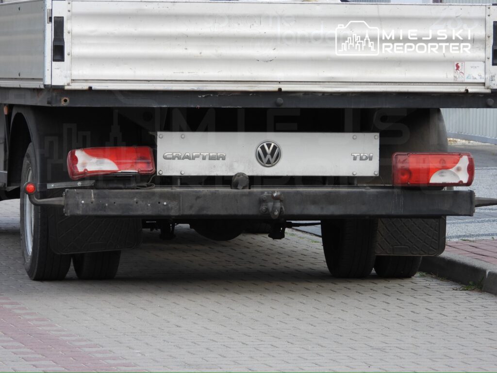 Volkswagen Crafter zaparkowany na kostce brukowej, widok od tyłu z widocznymi światłami i tablicą rejestracyjną.