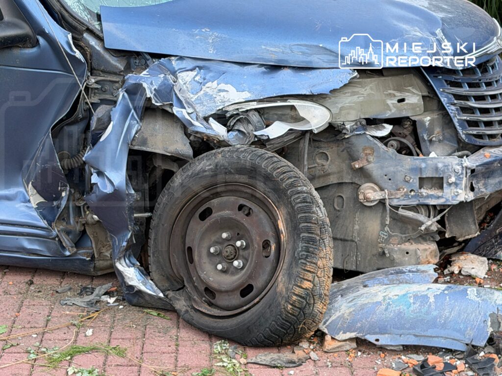 Uszkodzony samochód osobowy z zgniecioną karoserią i odłamkami na chodniku. Widać wyraźnie zniszczone koło i zarysowaną felgę.