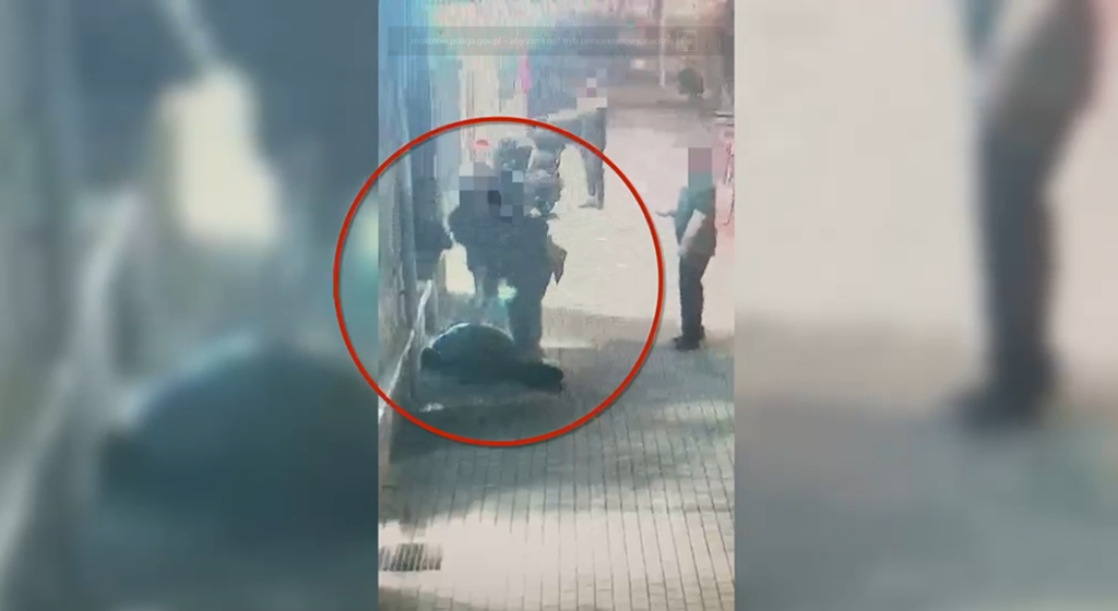 Grupa policjantów interweniuje przy leżącym mężczyźnie na chodniku w mieście, podczas nocnej akcji.