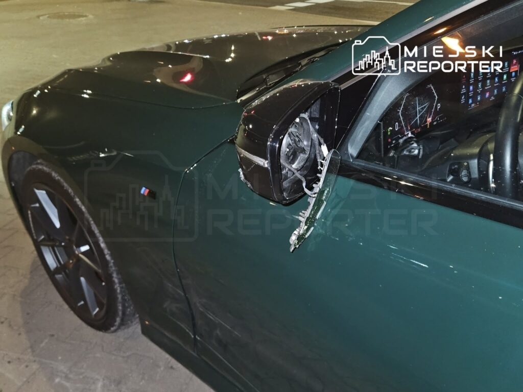 Złamana lusterko w samochodzie osobowym zaparkowanym na oświetlonym parkingu.