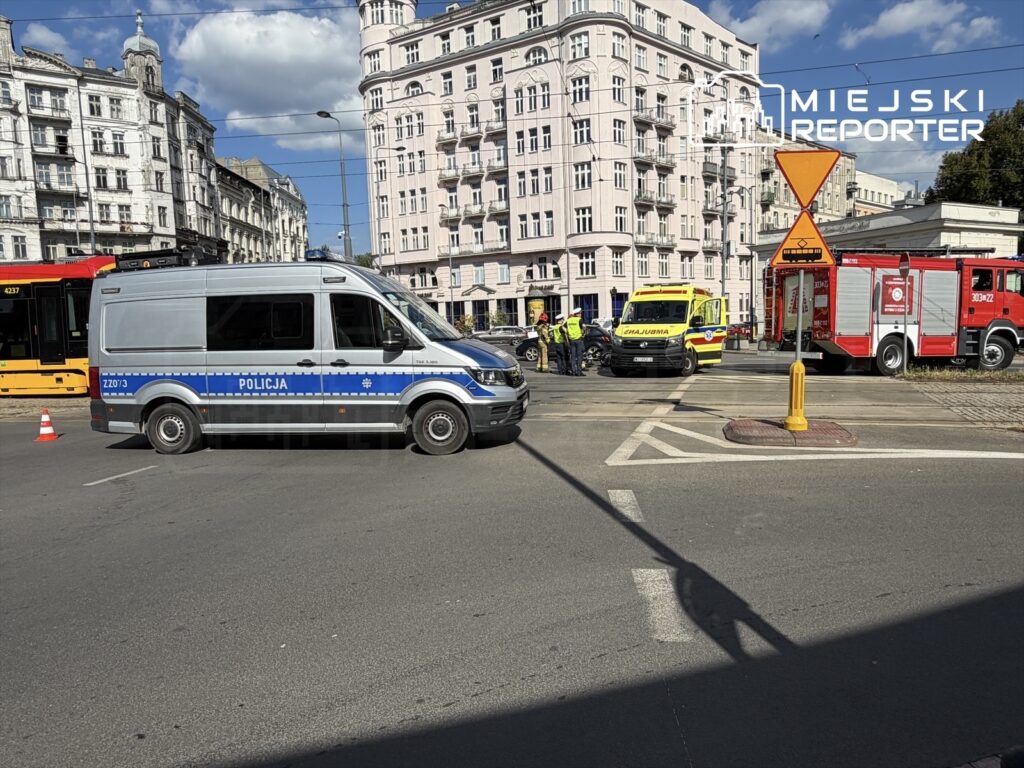 Policyjny furgon oraz karetka na Placu Unii Lubelskiej, obok pojazdów ratunkowych i grupy ratowników.