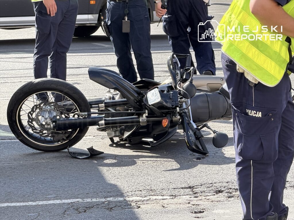 Motocyklista leży obok przewróconego motocykla, a policjanci prowadzą rozmowę na Placu Unii.
