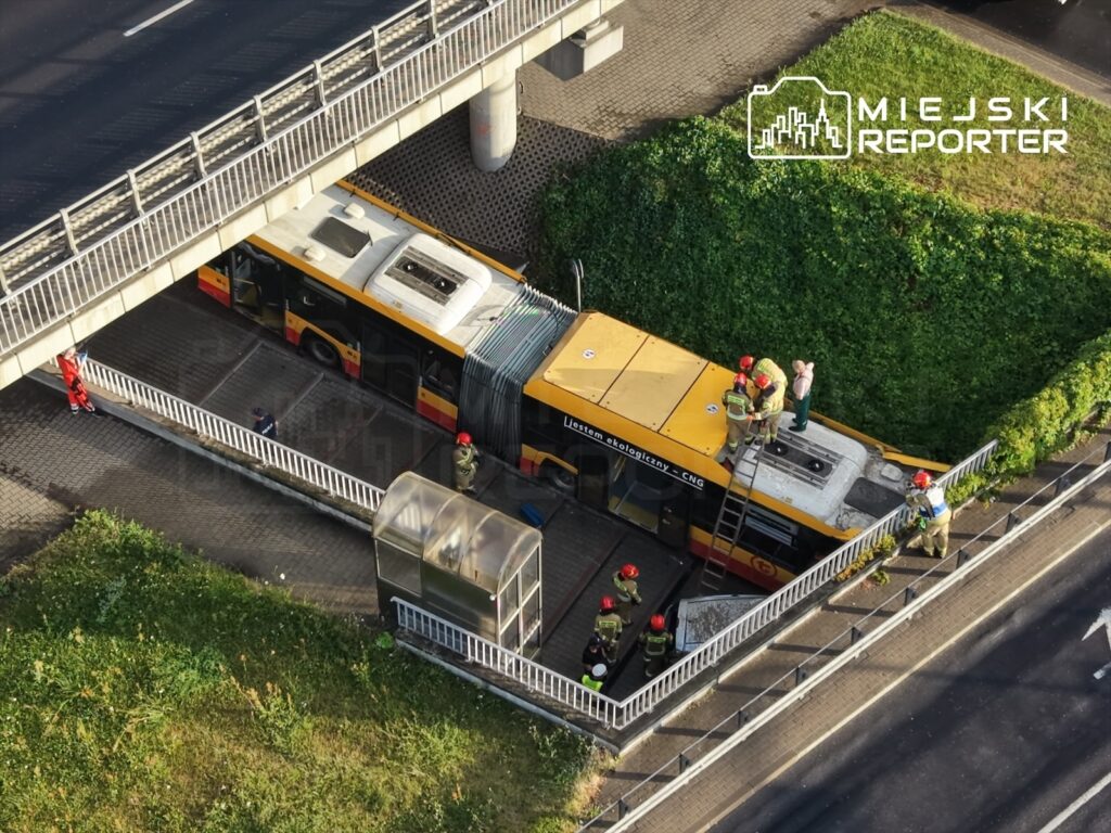 Grupa strażaków pracuje przy przystanku autobusowym, gdzie stoi uszkodzony autobus.