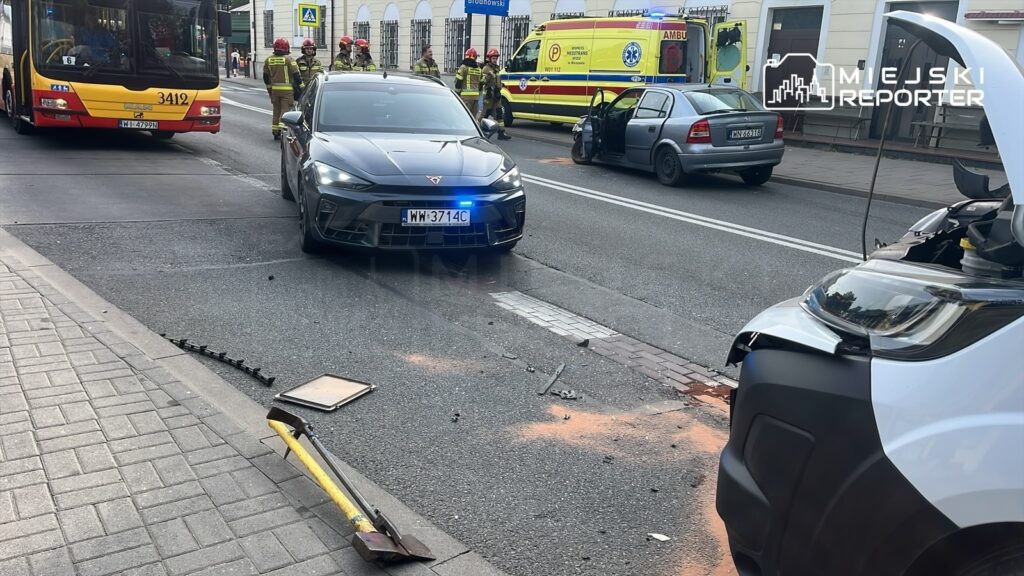 Na ulicy zablokowanej przez zderzenie, strażacy udzielają pomocy poszkodowanym w wypadku samochodowym.