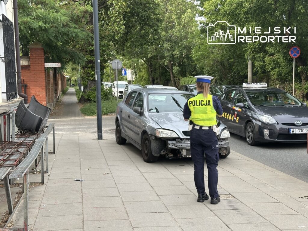 Policjantka w kamizelce odblaskowej rozmawia z kierowcą na ulicy św. Wincentego, w pobliżu cmentarza.