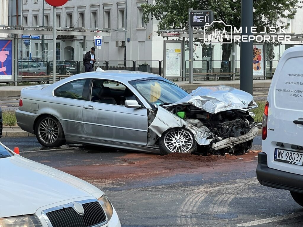 Zniszczony samochód osobowy marki BMW z wgniecionym tyłem stoi na jezdni, obok przystanku tramwajowego.