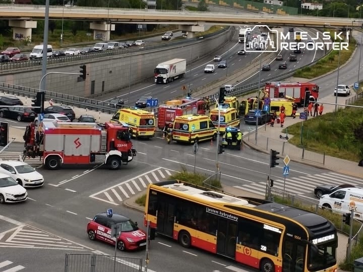 Wielka akcja ratunkowa na skrzyżowaniu, z licznymi pojazdami służb ratunkowych i zablokowanym ruchem.