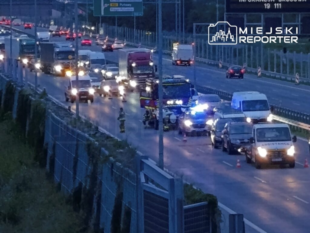 Kierowcy stoją w zatorze drogowym, podczas gdy służby ratunkowe udzielają pomocy na ruchliwej trasie.