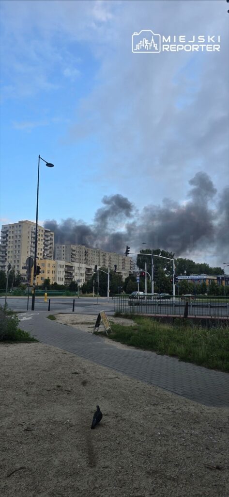 Kłęby czarnego dymu unoszą się nad nowoczesnymi budynkami mieszkalnymi w miejskim krajobrazie.