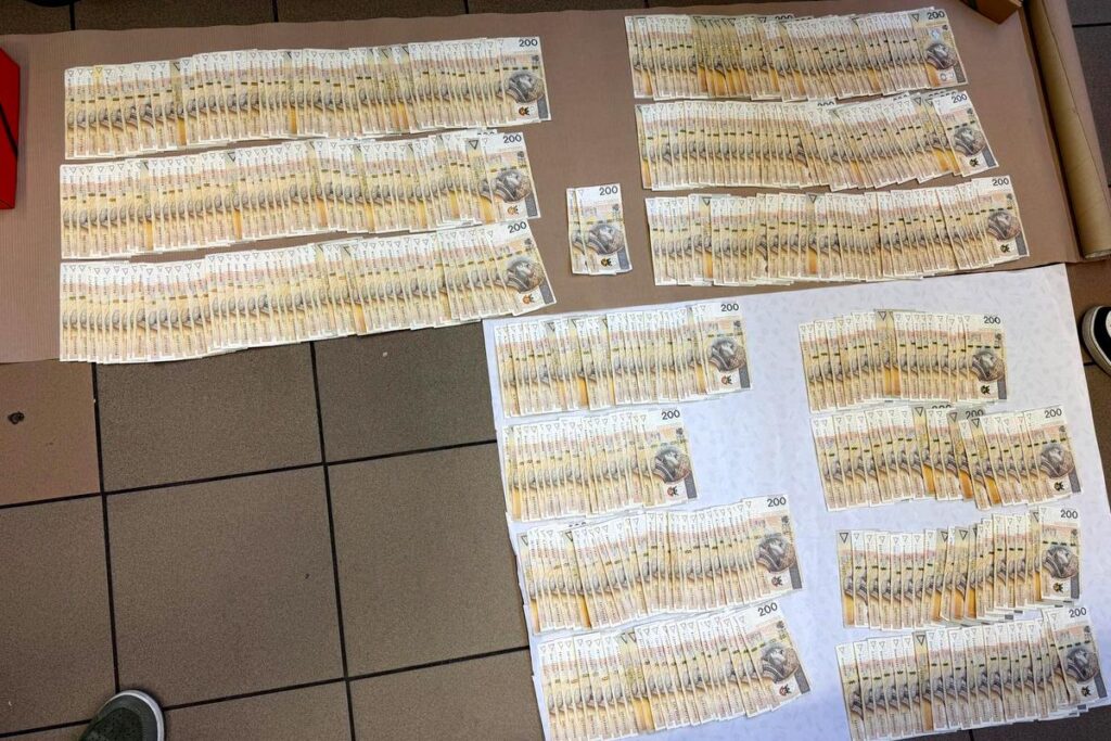 Setki banknotów o nominale 200 złotych ułożonych w równe stosy na podłodze w pomieszczeniu.