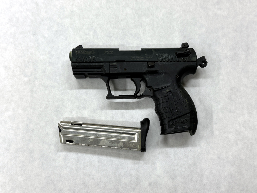 Pistolet z magazynkiem leżący na białym tle.