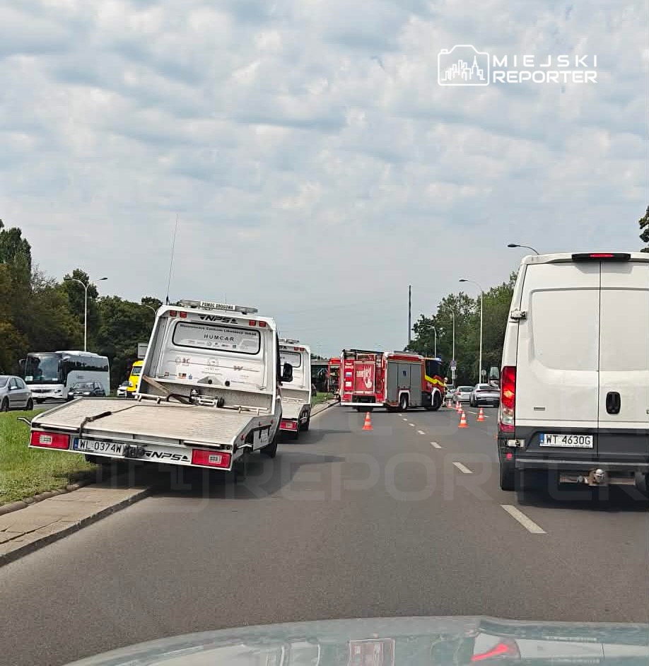 Na drodze stoi laweta z uniesioną rampą, obok pojazdy służb ratunkowych oraz wyznaczone strefy zabezpieczone pachołkami.