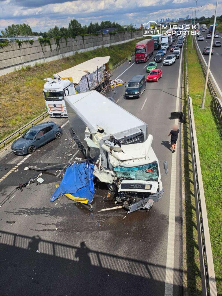 Wielka kolizja drogowa z udziałem ciężarówki i kilku pojazdów osobowych na autostradzie, z uszkodzonymi pojazdami i rozrzuconymi przedmiotami.