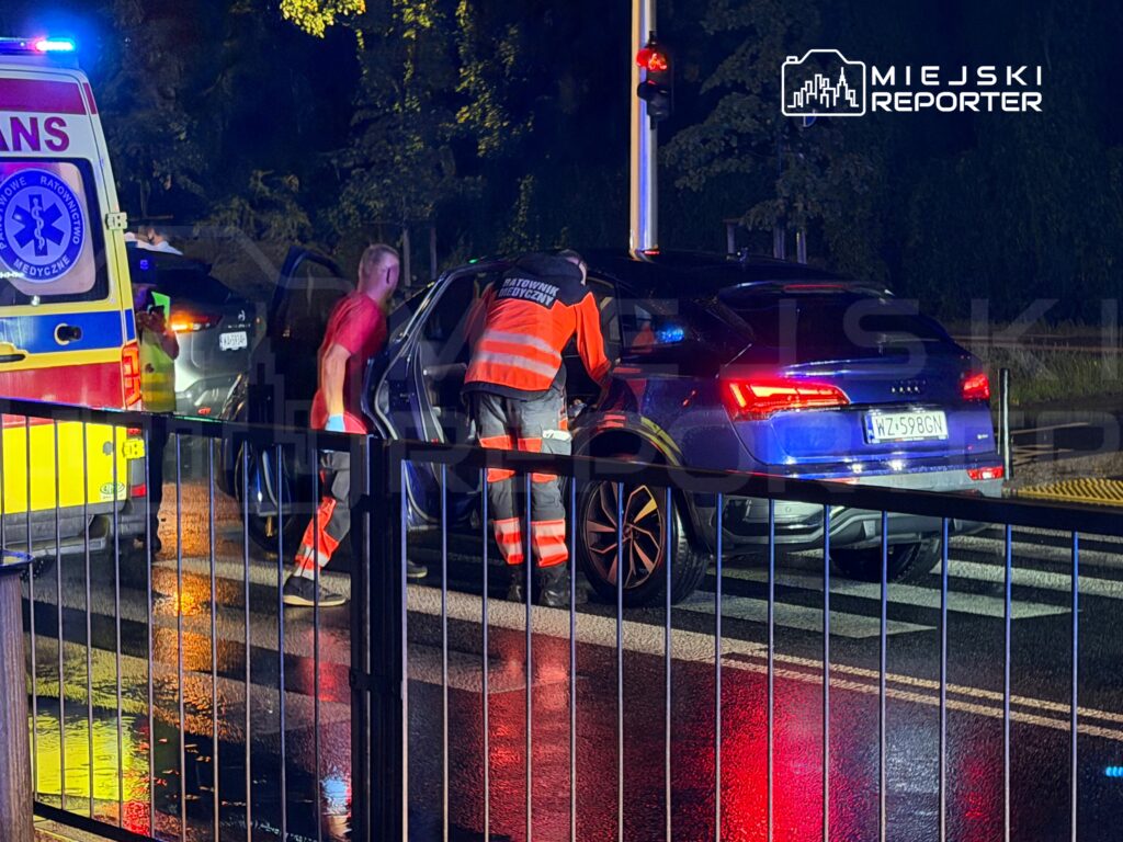 Ratownicy medyczni udzielają pomocy poszkodowanemu w samochodzie podczas nocnej interwencji na ulicy.