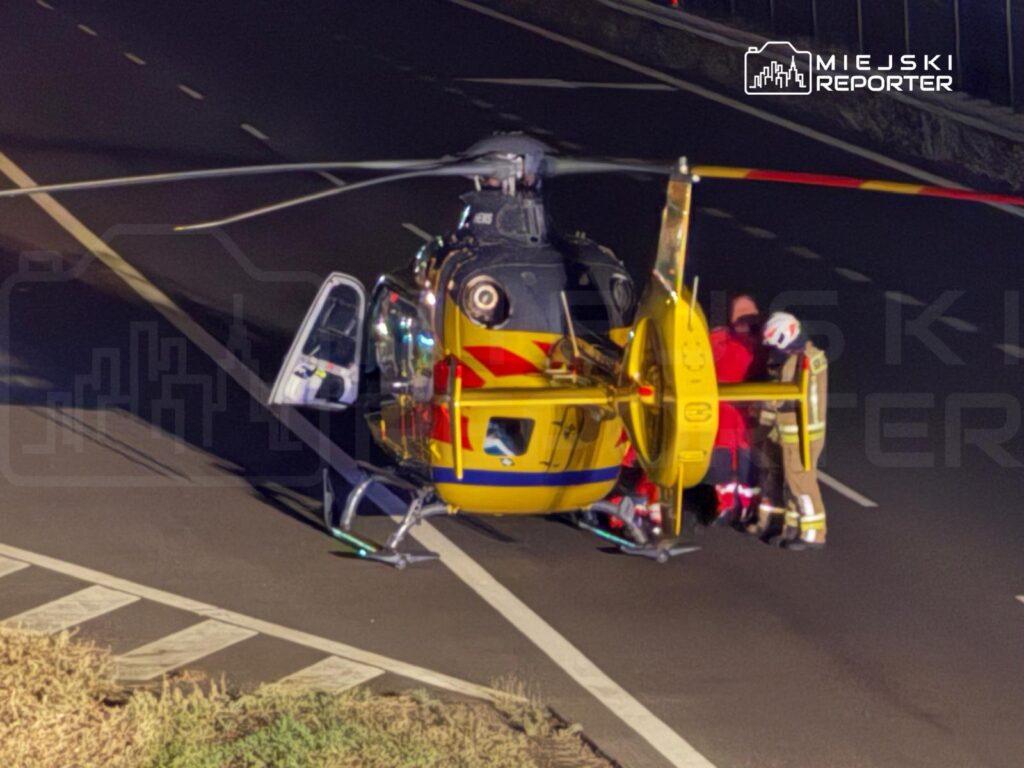 Zespół ratunkowy przygotowuje się do transportu poszkodowanego z helikoptera na drodze.
