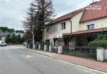 Przedszkole z kolorowym szyldem „Przedszkole z Złobek” znajdujące się w budynku z jasną elewacją, otoczone drzewami.