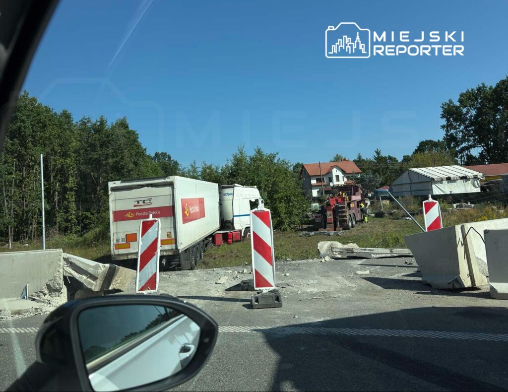 Ciężarówka z logo Poczty Polskiej stoi na drodze, obok widać pojazd pomocy drogowej oraz znaki ostrzegawcze.