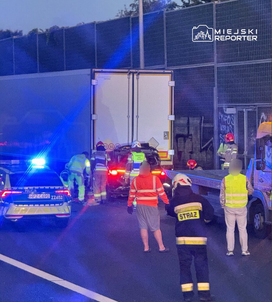 Na autostradzie zderzenie samochodu osobowego z ciężarówką; ratownicy i policja udzielają pomocy poszkodowanym.