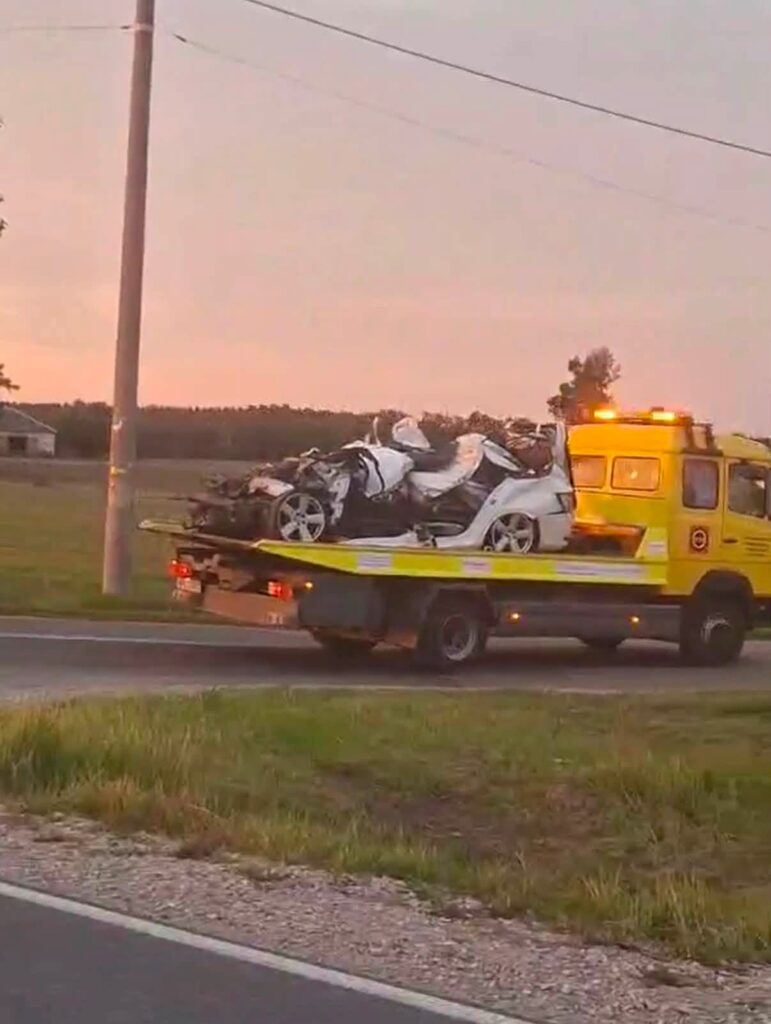 Laweta z uszkodzonymi pojazdami na drodze, w tle widoczny zachód słońca oraz pola.