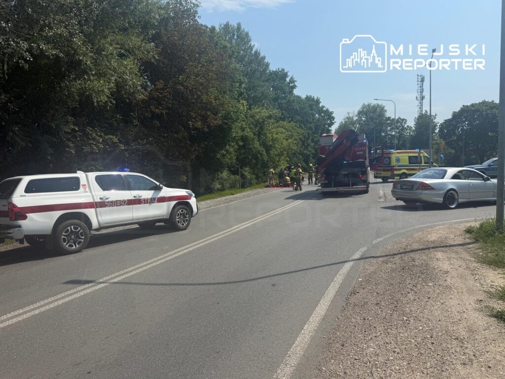 Na drodze krajowej 79, przy wypadku, pracują strażacy i ratownicy medyczni, obok stoją pojazdy służb.