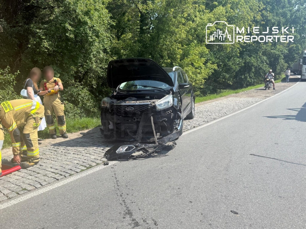 Strażacy udzielają pomocy przy zderzeniu drogowym na DK79, obok uszkodzonego czarnego SUV-a.